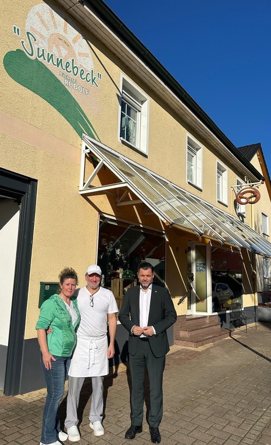 Anita Rudolf und Günter Rudolf gemeinsam mit Bürgermeister Andreas Heck vor der Bäcke-rei.